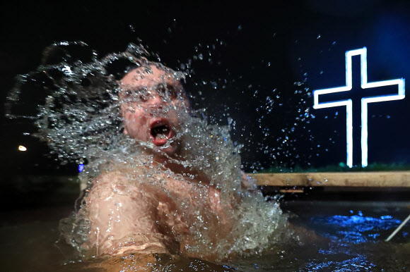 18일(현지시간) 정교회 신도가 러시아 콜피노에서 공현 대축일 전날 얼음물 속으로 뛰어들고 있다. 타스 연합뉴스