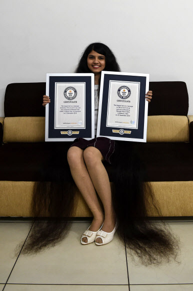 인도 구자라트 주의 여학생 닐란시 파텔(17)이 190㎝까지 머리카락을 길러 ‘가장 긴 머리카락-10대 부문’에서 자신이 2018년에 세웠던 기록을 경신했다. 들고 있는 기네스 기록 인증서 왼쪽이 2018년 기록, 오른쪽이 2019년 기록 인증서다. 2020.1.20  AFP 연합뉴스