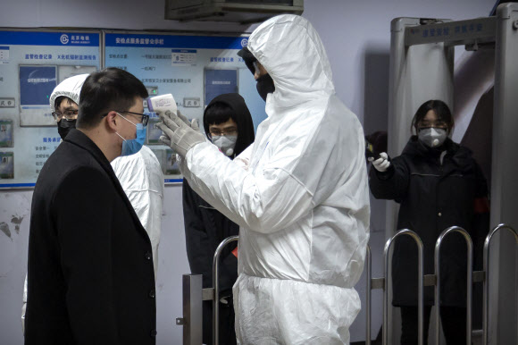 중국 베이징 전철역에서 위생방호복을 입고 있는 직원이 승객의 체온을 재고 있다. 2020.1.26  AP 연합뉴스