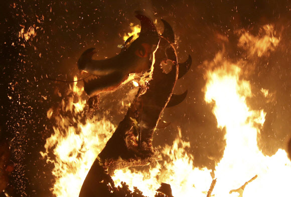 28일(현지시간) 스코틀랜드 러윅에서 ‘업 헬리 아(Up Helly Aa)’ 바아킹 축제가 열린 가운데 참가자들이 던진 횃불에 바이킹 함선이 불타고 있다. AP 연합뉴스