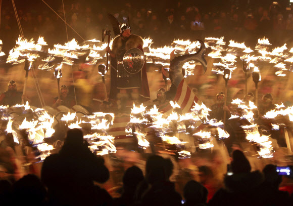 28일(현지시간) 스코틀랜드 러윅에서 ‘업 헬리 아(Up Helly Aa)’ 바아킹 축제가 열린 가운데 횃불을 든 참가자들이 바이킹 함선 주변에 모여있다. AP 연합뉴스