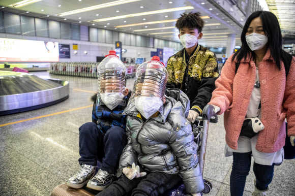어린이들이 1일(현지시간) 중국 광둥성 광저우 공항 입국 터미널에서 코로나 바이러스로부터 보호하기 위해 물병으로 만든 즉석 얼굴 보호 장치를 착용하고 있다. EPA 연합뉴스