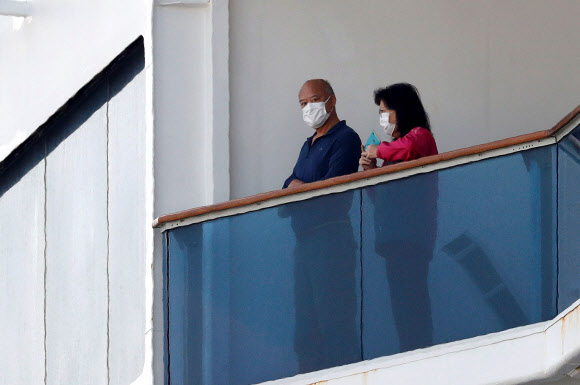 7일(현지시간) 일본 요코하마 다이코쿠 피어 크루즈 터미널에 정박해 있는 대형 크루즈선 ‘다이아몬드 프린세스’호의 승객들이 마스크를 쓰고 나와 있다. 로이터 연합뉴스