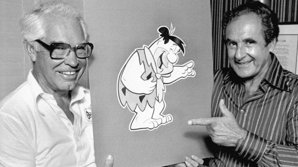 80년을 꾸준히 사랑 받는 캐릭터 ‘톰과 제리’를 만들어낸 빌 한나(왼족)와 조 바버라가 애니메이션 ‘플린트스톤’ 캐릭터 카드보드를 든 채 웃고 있다. AFP 자료사진