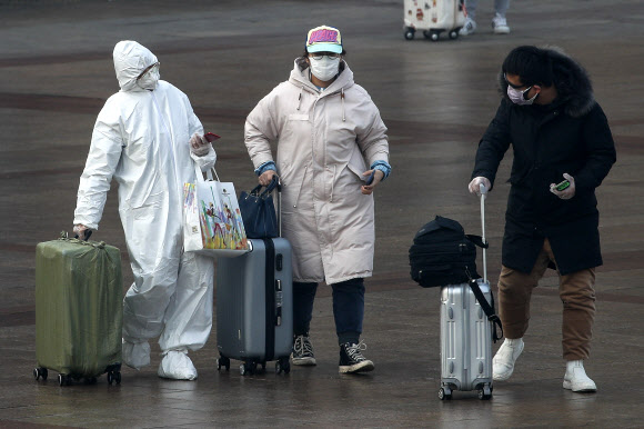 한 승객(왼쪽)이 11일(현지시간) 중국 베이징 기차역에서 전신보호복을 입고 걸어가고 있다. AP 연합뉴스