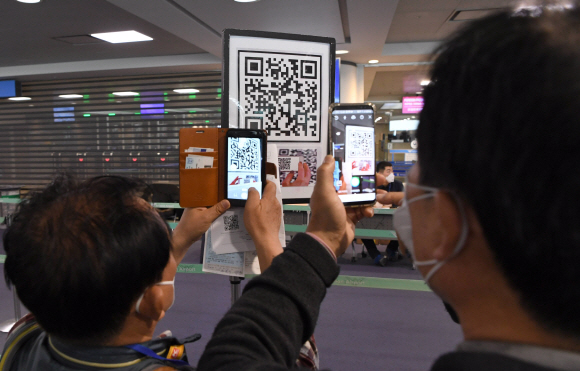 홍콩과 마카오가 코로나-19 오염지역으로 지정돼 홍콩과 마카오에 대한 특별입국절차가 개시된 13일 인천 중구 인천국제공항에서 홍콩 발 항공편 승객들이 ‘자가진단 앱’ 설치를 하고 있다. 2020. 2.13 공항사진기자단