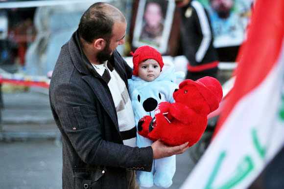 한 남성이 13일(현지시간) 이라크 바그다드에서 아이에게 발렌타인 데이 선물을 주고 있다. AP 연합뉴스