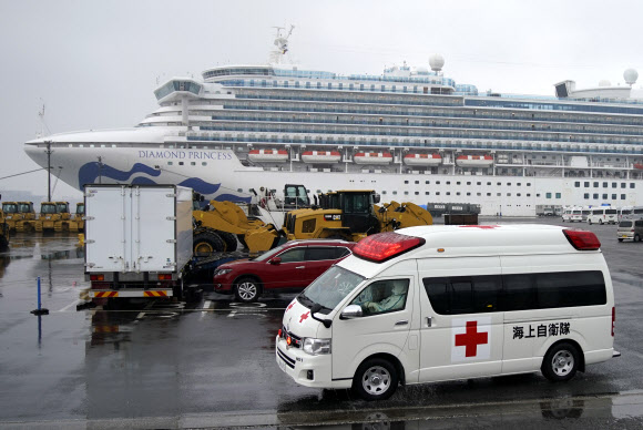 일본 요코하마 앞바다에 격리된 채 정박 중인 크루즈 유람선 ‘다이아몬드 프린세스’에서 16일 코로나19(신종 코로나바이러스 감염증) 확진환자를 이송하는 것으로 추정되는 구급차가 항구를 빠져나가고 있다. 요코하마 EPA 연합뉴스
