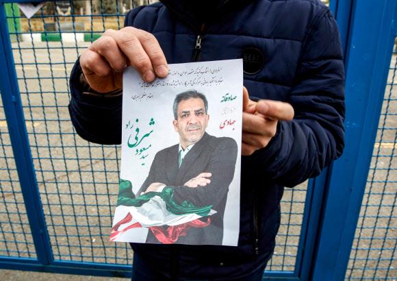 ‘중동의 맹주’ 이란이 오는 21일 총선을 앞두고 선거 정국에 들어갔다. 지난 15일(현지시간) 수도 테헤란에 있는 한 이슬람사원 바깥에서 한 남성이 선거 유인물을 들어 보이고 있다.  테헤란 AFP 연합뉴스