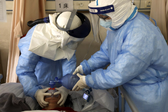 16일 중국 후베이성 우한의 한 병원에서 방호복을 입은 의료진들이 코로나19(신종 코로나바이러스 감염증)에 감염된 환자에게 산소 공급을 하고 있다. 2020.2.18  AP 연합뉴스