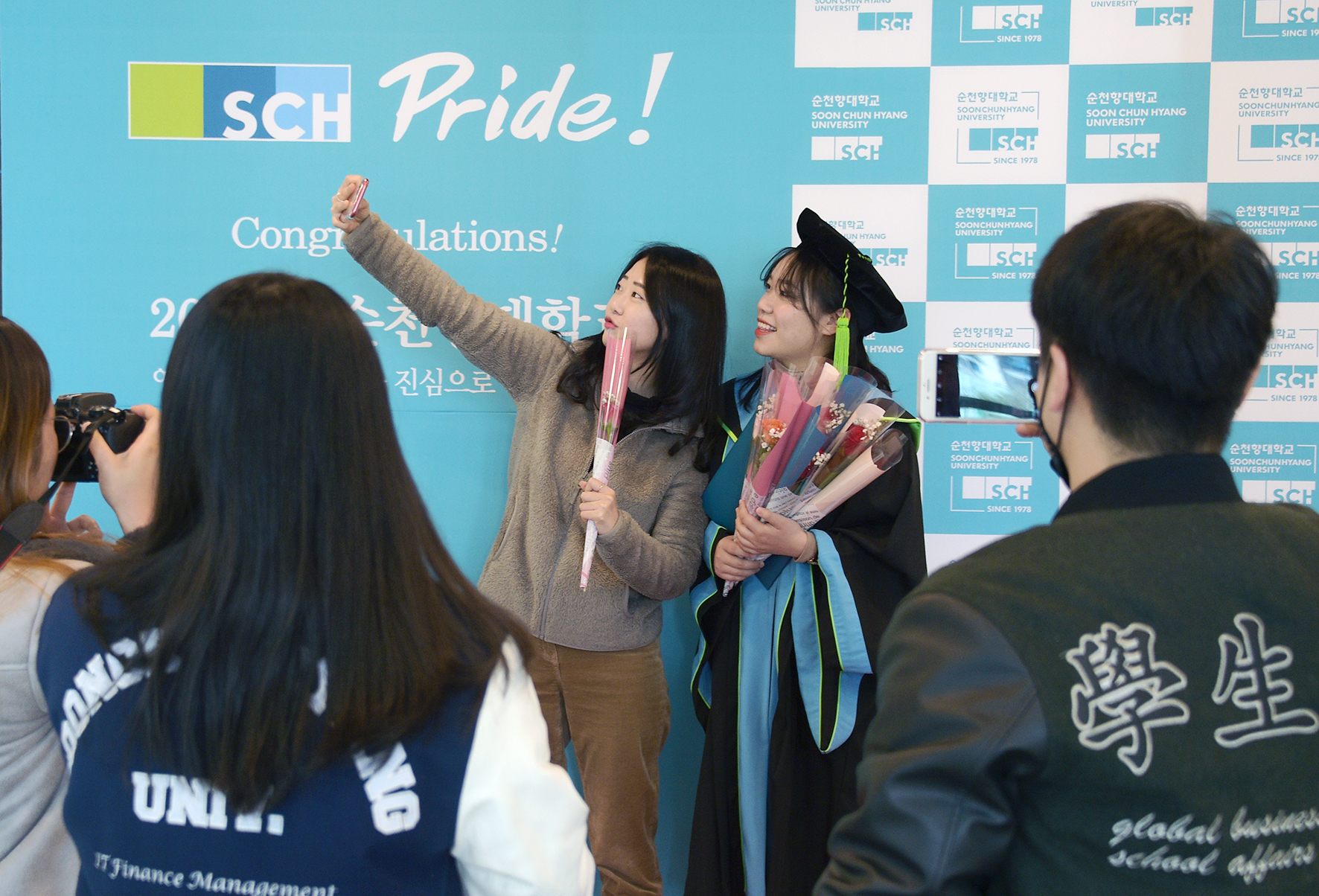 순천향대 졸업생이 단과대에 설치된 포토존에서 졸업가운을 입고 후배들의 축하 속에 개별적으로 졸업사진을 찍고 있다. 순천향대 제공