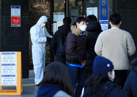 신종코로나바이러스감염증(코로나19)이 확산되는 가운데 23일 오전 서울 성동구 한양대학교에 마련된 공인회계사(CPA) 1차시험장에서 방진복과 마스크를 쓴 시험 관계자가 응시생들을 안내하고 있다. 2020.2.23  연합뉴스