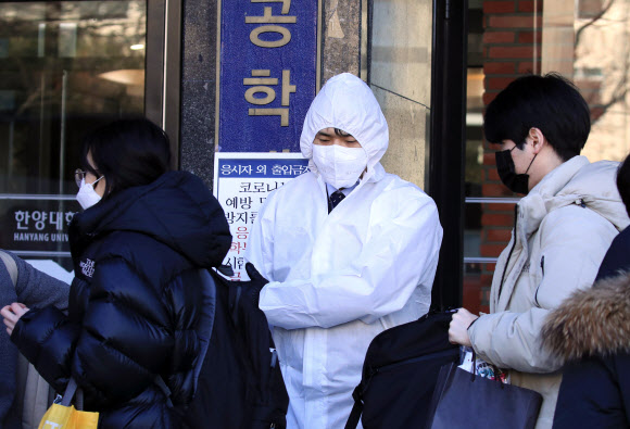 신종코로나바이러스감염증(코로나19)이 확산되는 가운데 23일 오전 서울 성동구 한양대학교에 마련된 공인회계사(CPA) 1차시험장에서 방진복과 마스크를 쓴 시험 관계자가 응시생들을 안내하고 있다. 2020.2.23  연합뉴스