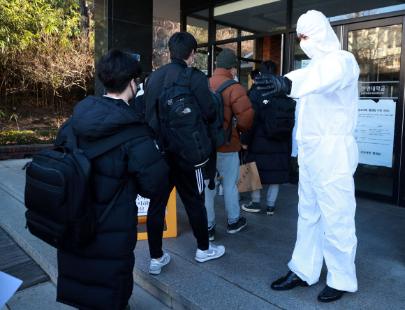 신종코로나바이러스감염증(코로나19)이 확산되는 가운데 23일 오전 서울 성동구 한양대학교에 마련된 공인회계사(CPA) 1차시험장에서 방진복과 마스크를 쓴 시험 관계자가 응시생들을 안내하고 있다. 2020.2.23  연합뉴스