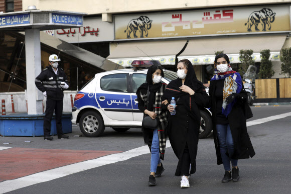 이란 수도 테헤란 도심에서 경찰관과 여성들이  마스크를 쓴 모습. 테헤란 AP 연합뉴스