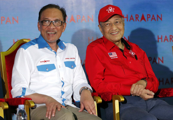 24일 갑자기 총리 직에서 물러난다고 발표한 마하티르 모하마드(오른쪽) 말레이시아 총리가 지난해 10월 8일 포트 딕슨 유세 도중 안와르 이브라힘과 나란히 앉아 있다. 다시 권좌에 앉기 위해 안와르와 손을 잡았다가 이제 권력을 물려주기 싫어 총리에서 물러난 뒤 총선을 실시해 권력을 혼자 거머쥐겠다는 마하티르의 구상인 것처럼 보인다. AP 자료사진 연합뉴스 