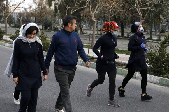   이란의 두 여성이 28일(현지시간) 수도 테헤란의 파르디산 공원에서 마스크를 쓴 채 조깅을 하자 걷던 남성이 흘깃 쳐다보고 있다. 이란의 31개 주(州) 가운데 23개 주도에서 금요 대예배가 열리지 않고 대학, 학교, 의회 등이 일제히 문을 닫아 시민들은 공원 등에서 주말을 보냈다. 테헤란 AP 연합뉴스 