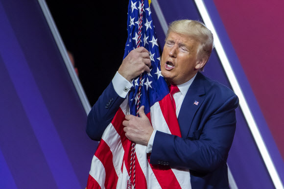 도널드 J. 트럼프 미국 대통령이 29일(현지시간) 미국 메릴랜드주 내셔널 하버에서 열린 ‘제 47회 보수정치행동회의(CPAC)(the 47th annual Conservative Political Action Conference (CPAC))’에서 연설 후, 미국 국기를 껴안고 있다. EPA 연합뉴스