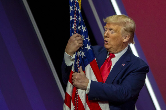 도널드 J. 트럼프 미국 대통령이 29일(현지시간) 미국 메릴랜드주 내셔널 하버에서 열린 ‘제 47회 보수정치행동회의(CPAC)(the 47th annual Conservative Political Action Conference (CPAC))’에서 연설 후, 미국 국기를 껴안고 있다. 게티/AFP 연합뉴스