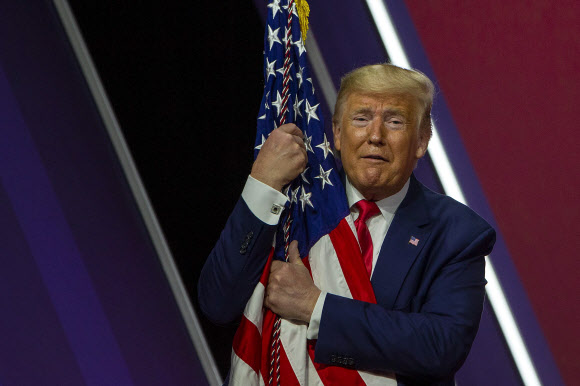 도널드 J. 트럼프 미국 대통령이 29일(현지시간) 미국 메릴랜드주 내셔널 하버에서 열린 ‘제 47회 보수정치행동회의(CPAC)(the 47th annual Conservative Political Action Conference (CPAC))’에서 연설 후, 미국 국기를 껴안고 있다. 게티/AFP 연합뉴스