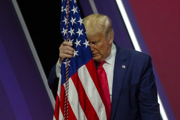 도널드 J. 트럼프 미국 대통령이 29일(현지시간) 미국 메릴랜드주 내셔널 하버에서 열린 ‘제 47회 보수정치행동회의(CPAC)(the 47th annual Conservative Political Action Conference (CPAC))’에서 연설 후, 미국 국기에 이마를 대고 있다. 게티/AFP 연합뉴스