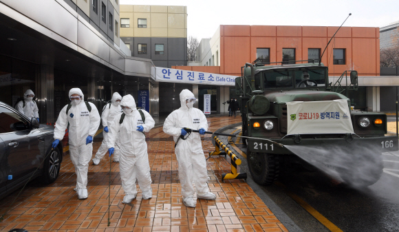 코로나 19 확산이 지속되는 4일 서울 강남구 서울성모병원 내 선별진료소 앞에서 서초구청 관계자들과 국군화생방방호사령부 특임대 도로건물방역팀이 신형 제독차와 중형 제독기를 이용해 방역 작업을 하고 있다. 2020.3.4 오장환 기자 5zzang@seoul.co.kr