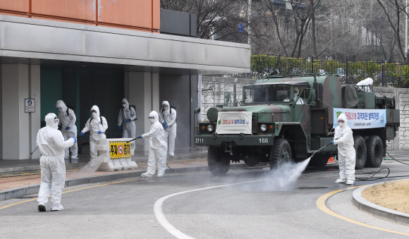 코로나 19 확산이 지속되는 4일 서울 강남구 서울성모병원 내 선별진료소 앞에서 서초구청 관계자들과 국군화생방방호사령부 특임대 도로건물방역팀이 신형 제독차와 중형 제독기를 이용해 방역 작업을 하고 있다. 2020.3.4 오장환 기자 5zzang@seoul.co.kr