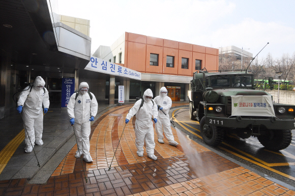 코로나 19 확산이 지속되는 4일 서울 강남구 서울성모병원 내 선별진료소 앞에서 서초구청 관계자들과 국군화생방방호사령부 특임대 도로건물방역팀이 신형 제독차와 중형 제독기를 이용해 방역 작업을 하고 있다. 2020.3.4 오장환 기자 5zzang@seoul.co.kr