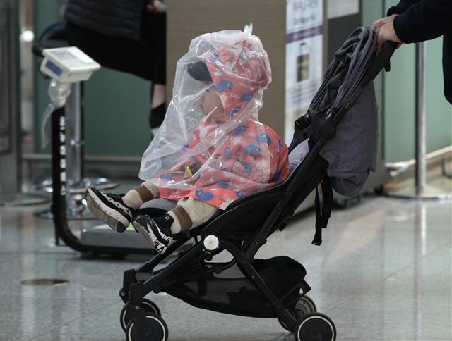 신종 코로나바이러스 감염증(코로나19)이 확산하고 있는 가운데 5일 인천국제공항 1터미널에서 한 어린이가 비닐을 뒤집어쓰고 출국장으로 향하고 있다. 2020.3.5 뉴스1