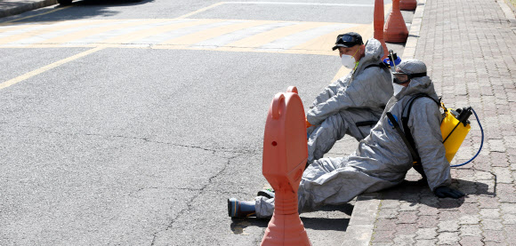 6일 오전 울산시 북구 화봉동 한 아파트 단지 안에서 신종 코로나바이러스 감염증(코로나19) 확산 방지를 위한 방역에 나선 북구청 공무원들이 휴식을 취하고 있다. 2020.3.6  연합뉴스