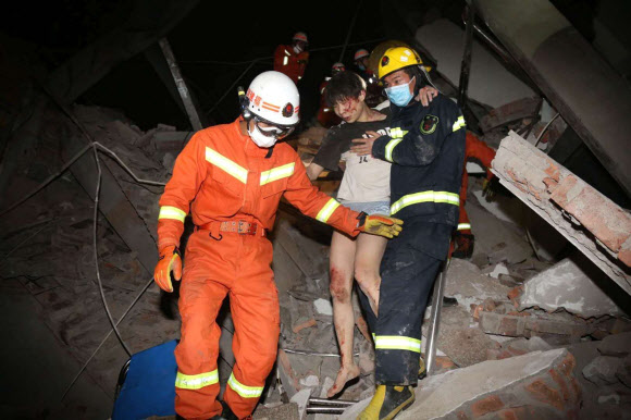중국 구조요원들이 7일 저녁 무너져내린 푸젠성 취안저우의 코로나19 격리 시설 건물 잔해 더미에서 여성을 구조해 부축해 걸어나오고 있다. 취안저우 AP 연합뉴스 