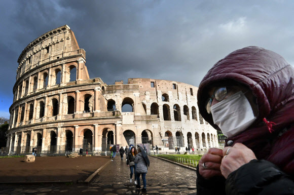 중국 외 코로나19 사망자(233명)가 가장 많은 이탈리아의 로마 콜로세움에서 7일(현지시간) 한 관광객이 마스크를 쓴 채 걸어가고 있다. 현지 언론에 따르면 이탈리아 관광협회는 3월에만 2억 유로(약 2695억원) 규모의 여행 및 숙박 예약이 취소됐다고 전했다. 로마 AFP 연합뉴스