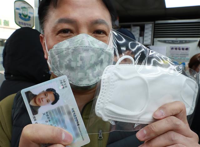 마스크 5부제가 시행된 9일 오전 서울 종로구의 한 대형 약국에서 마스크를 구매한 시민이 마스크와 신분증을 들고 있다. 마스크 5부제에 따라 출생연도 끝자리가 1·6이면 월요일, 2·7 화요일, 3·8 수요일, 4·9 목요일, 5·0은 금요일에 살 수 있으며 평일에 구매하지 못했다면 주말 중 하루를 골라 살 수 있다. 2020.3.9 뉴스1