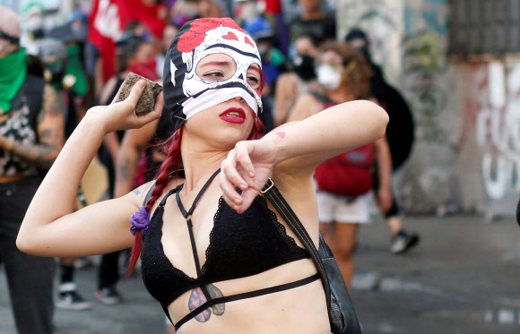 ‘세계 여성의 날’인 8일(현지시간) 칠레 산티아고에서 열린 대규모 집회에서 참가자가 시위중 돌을 던질 준비를 하고 있다. 로이터 연합뉴스