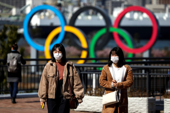코로나19가 확산되고 있는 일본에서 지난 27일 도쿄 시민들이 오륜 조형물 앞을 마스크를 쓴 채 지나가고 있다. 도쿄 로이터 연합뉴스