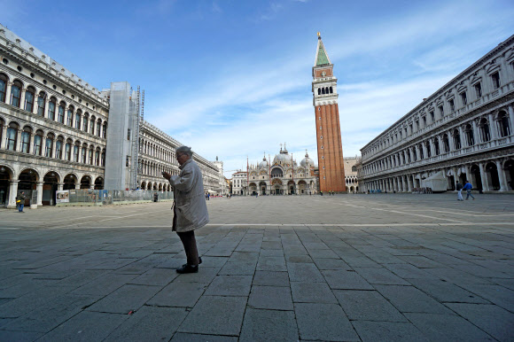 한 여성이 이탈리아 정부의 사실상 봉쇄 정책이 시행된 첫날인 9일(현지시간) 베네치아의 성 마르코 광장을 지나가고 있다. 베네치아 AP 연합뉴스 