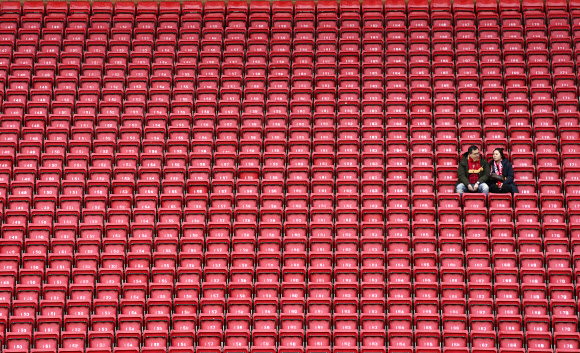 지난 7일(현지시간) 영국 리버풀의 안필드 경기장에서 프리미엄리그 축구 경기를 기다리는 두 사람 주위에 모든 좌석이 텅 비어 있다. AP통신