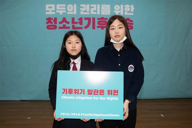 ‘청소년 기후행동’의 김유진(왼쪽)양, 성경운씨가 지난 13일 ‘기후위기 방관은 위헌’이라고 적힌 피켓을 든 모습.  청소년 기후행동 제공