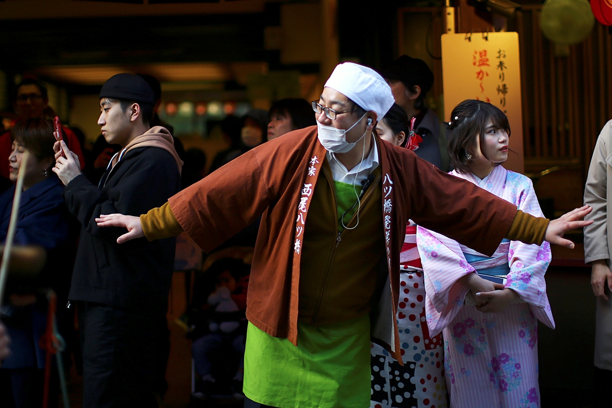 15일 일본 교토의 한 거리에서 코로나19 예방 마스크를 쓴 주방장이 거리로 나와 호객을 하고 있다. 마스크를 쓸 땐 입은 물론 코도 완전히 가려야 차단 효과가 있다. 2020.3.15  로이터 연합뉴스