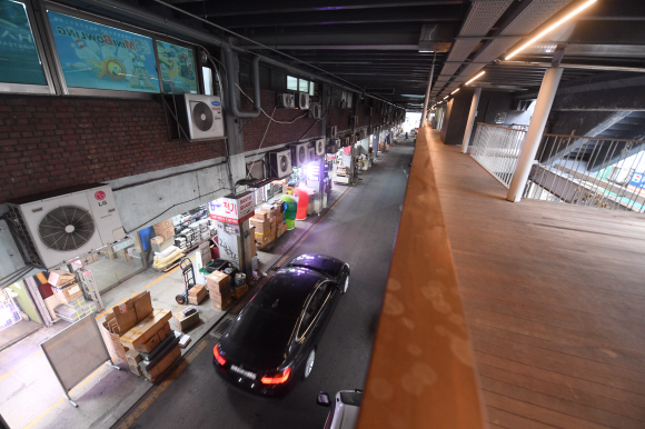 원래 차량 전용도로로 계획했던 1층에 비좁은 상점, 인도, 적치장, 1차선 차로와 주차장이 들어서 있다. 오른쪽에 다시세운 프로젝트의 일환으로 가설한 보행 데크가 2층에 떠 있다.   정연호 기자 tpgod@seoul.co.kr