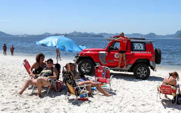 신종 코로나바이러스 감염증(코로나19) 확산에 대한 대책이 발표된 3일(현지시간) 브라질 리우데자네이루 플라멩고 해변에서 구조대원들이 선텐을 즐기는 사람들에게 경고하고 있다. 로이터 연합뉴스