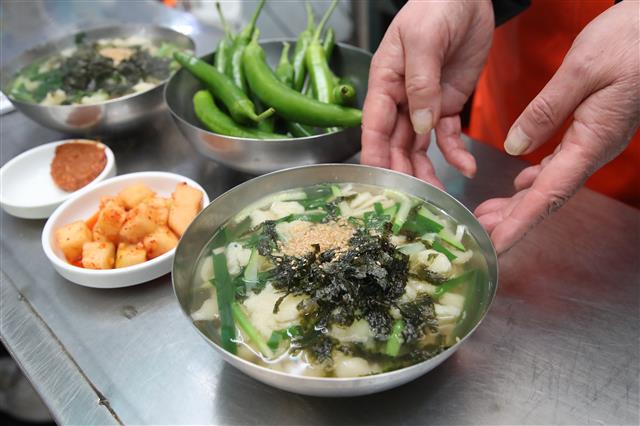 신종 코로나바이러스 감염증(코로나19) 확산으로 영업을 중단했던 대구 서문시장 상인들이 17일 정오 무렵 점심 손님을 맞이하며 새로운 출발을 준비하고 있다.  한 상인이 칼국수와 수제비를 섞은 메뉴 칼제비를 차려내고 있다. 2020.3.17 뉴스1