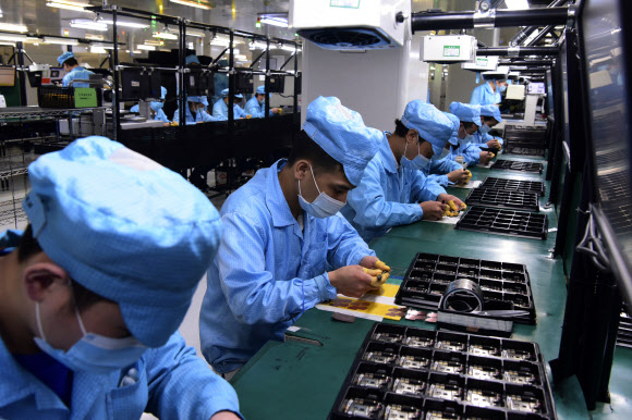 코로나19 충격으로 중국 기업들이 큰 어려움을 겪고 있는 가운데 지난 13일 중국 남부 광둥성 둥관에 있는 중국 스마트폰 제조업체 오포의 생산 공장에서 마스크를 낀 직원들이 작업에 열중하고 있다. 둥관 신화 AP 연합뉴스