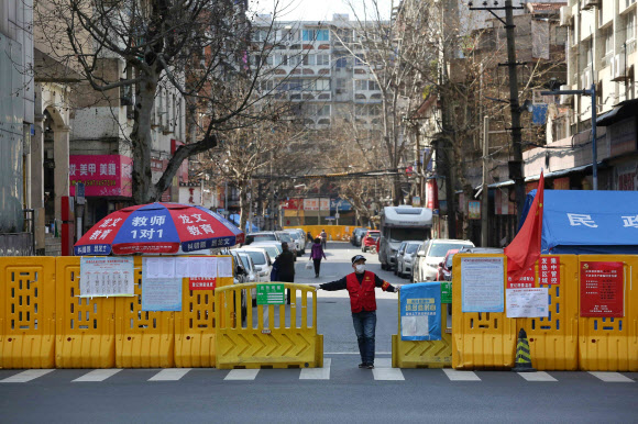중국 우한시 자원봉사자가 지난 15일 사람들 출입을 막기 위해 설치된 격벽 문을 닫고 있다. 우한 AFP 연합뉴스