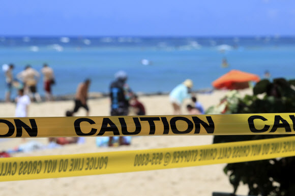 사람들이 20일(현지시간) 미국 하와이주 호놀룰루의 노란색 경고 테이프로 둘러싸인 와이키키 해변에서 즐거운 시간을 보내고 있다. 호놀룰루는 코로나바이러스의 확산을 막기 위해 모든 공원과 휴양지를 폐쇄했다. AP 연합뉴스