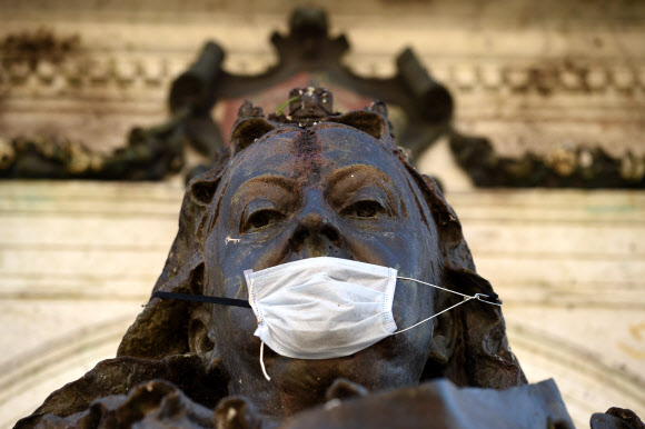 퀸 빅토리아 동상이 20일(현지시간) 영국 북부 맨체스터 피카딜리 가든의 에서 새로운 코로나바이러스 COVID-19 대유행에 대한 예방책으로 사용되는 마스크를 쓰고 있다. AFP 연합뉴스