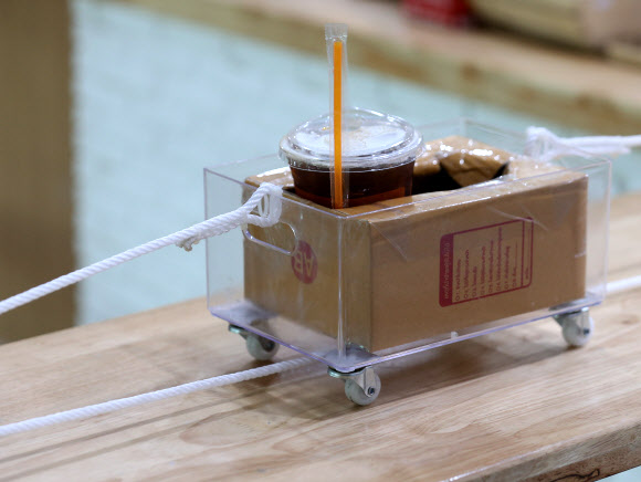 직원이 21일(현지시간) 태국 방콕의 카세타트 대학 내 커피숍에서 사람들 사이의 사회적 거리를 보장하기 위해 도르래 시스템을 사용해 음료를 전달하고 있다. EPA 연합뉴스