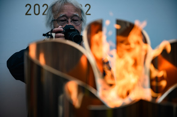 한 시민이 22일(현지시간) 일본 이와테현 미야코 철도역 밖에 전시된 ‘2020 도쿄 올림픽’ 성화 앞에서 기념촬영을 하고 있다. AFP 연합뉴스