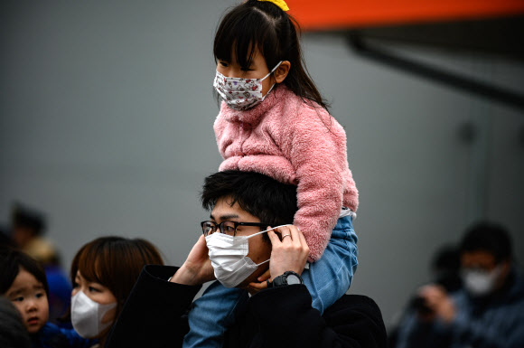 마스크를 쓴 시민들이 22일(현지시간) 일본 이와테현 미야코 철도역 밖에 전시된 ‘2020 도쿄 올림픽’ 성화를 구경하고 있다. AFP 연합뉴스