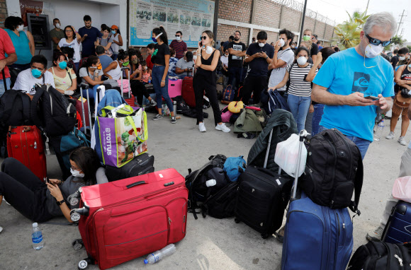 신종 코로나바이로스 감염증(코로나19) 확산 방지를 위해 페루 정부가 국가비상사태를 선포하고 국경을 폐쇄한 가운데 페루를 떠나려는 여행객들이 22일(현지시간) 전세기를 타기 위해 페루 리마의 군사공항에서 줄지어 기다리고 있다. 로이터 연합뉴스